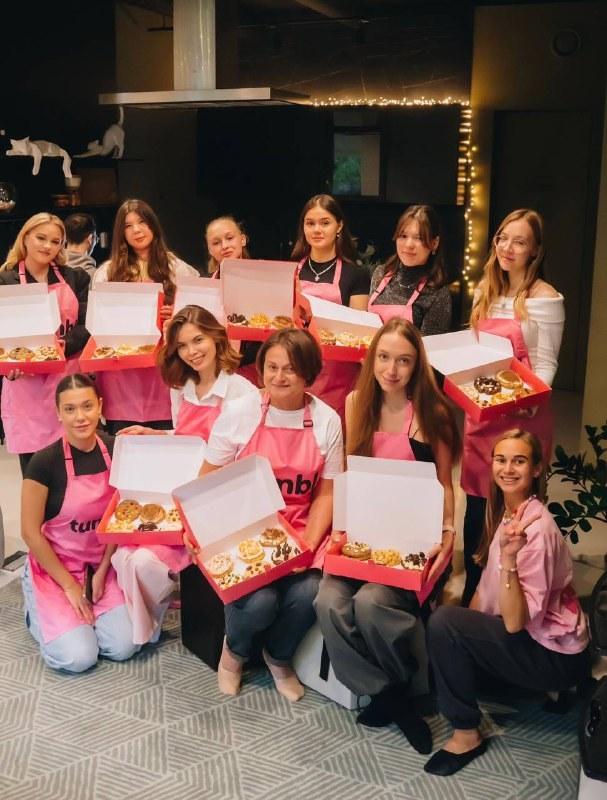 Девушки в розовых фартуках с коробками печенья кукис